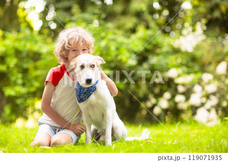 Child playing with a dog in sunny summer garden 119071935