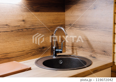 Modern kitchen sink with wooden countertop, showcasing contemporary design and minimalist style 119072042