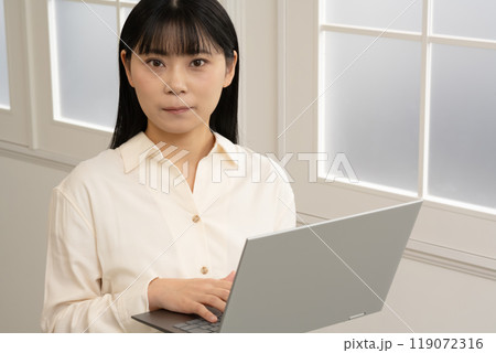 立ってノートパソコンの操作をする女性 119072316