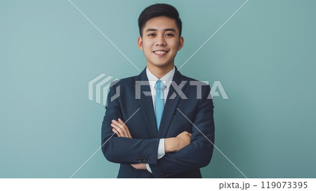 Confident Young Southeast Asian Businessman Standing Against Blue Background for Corporate and Professional Use 119073395