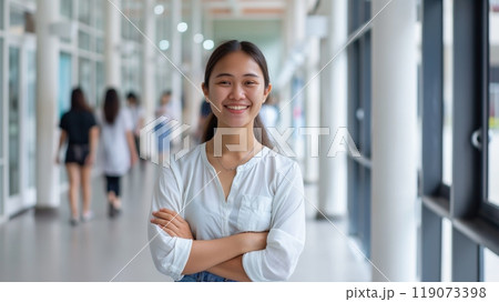 Smiling Indonesian Female Student in White Blouse Standing in Modern University Hallway Smiling Indonesian Female Student in White Blouse Standing in Modern University Hallway 119073398