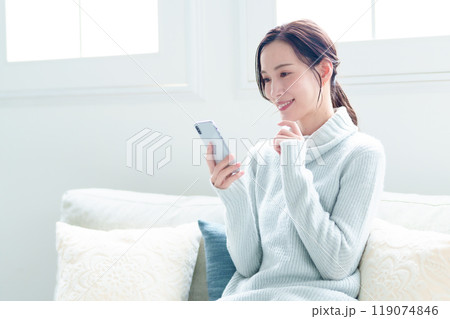 リビングでスマートフォンを使う女性 リビングでスマートフォンを使う女性 119074846