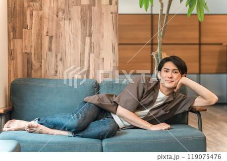 ソファに寝転ぶ若いアジア人男性 119075476
