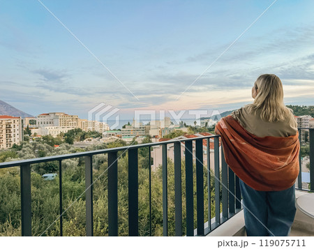 A woman standing on the balcony at summer sunset 119075711
