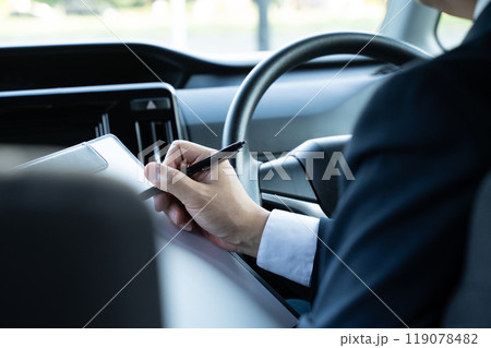 運転席で書類を書く男性の手元 運転席で書類を書く男性の手元 119078482