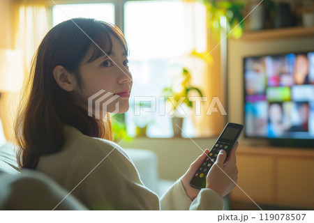 テレビのリモコンを持つ若いアジア人女性 119078507