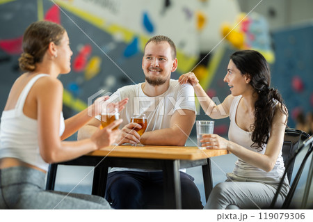 Man and two girls meet after rock climbing training - discussing successes and failures together at table, chatting and drinking beer 119079306