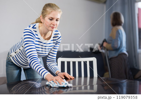 Adult daughter and her mature mother clean the room 119079358