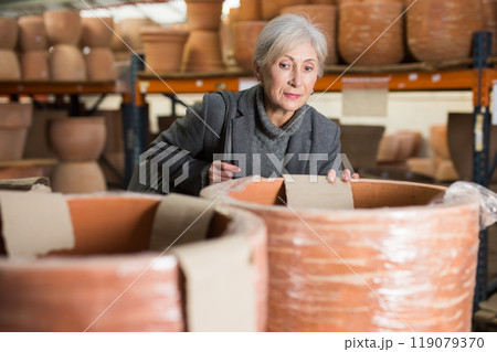 Aged woman selecting decorative earthenware pot in shop Aged woman selecting decorative earthenware pot in shop 119079370