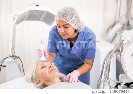 Old woman having face laser therapy procedure 119079445