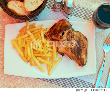 Roasted chicken with fries served with glass of red wine 119079519