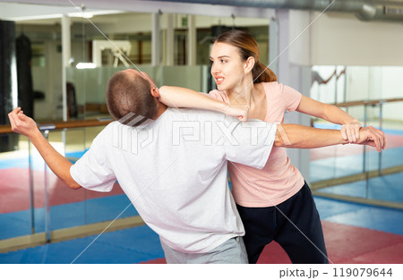 Active girl conducts painful grip on self-defense training in gym 119079644