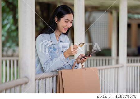 Savvy Shopper Smiling While Using Card and Smartphone for Black Friday Online Shopping 119079679