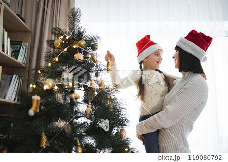 Mother and daughter decorating Christmas tree with joy 119080792