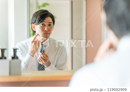 朝出勤前に洗面所で髭剃りをするスーツ姿の若いアジア人ビジネスマン 119082909