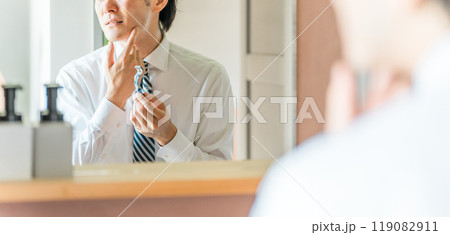 朝出勤前に洗面所で髭剃りをするスーツ姿の若いアジア人ビジネスマン 119082911