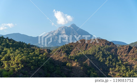 Tahtali Olympos mountain peak as seen from the Lycian Way in Cirali, Antalya, Turkey. The scenic landscape features lush forests, blue skies, and rugged slopes. 119083752