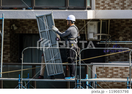マンションの大規模修繕工事現場で安全第一に足場架設工事を行う鳶職人 マンションの大規模修繕工事現場で安全第一に足場架設工事を行う鳶職人 119083798