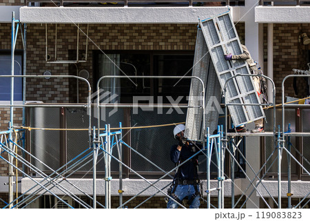 マンションの大規模修繕工事現場で安全第一に足場架設工事を行う鳶職人 マンションの大規模修繕工事現場で安全第一に足場架設工事を行う鳶職人 119083823