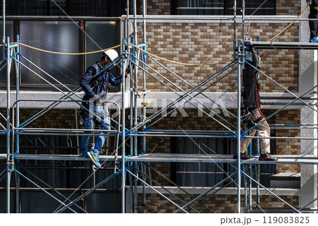 マンションの大規模修繕工事現場で安全第一に足場架設工事を行う鳶職人 マンションの大規模修繕工事現場で安全第一に足場架設工事を行う鳶職人 119083825