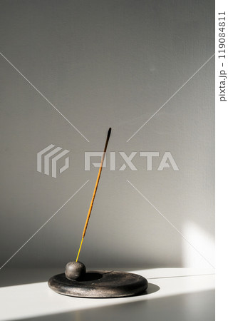 Burning incense stick and smoke with contrast shadows. 119084811