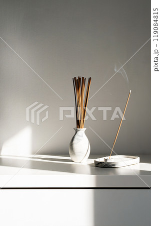 Incense stick with smoke in holder with contrast shadows. 119084815