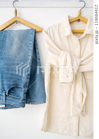 Shirt and jeans hanging on wooden hangers. Casual fashion concept. 119084817