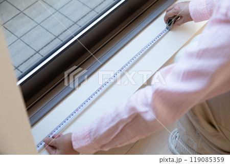 マンションの窓辺でカーテンのサイズを測るミドル女性 マンションの窓辺でカーテンのサイズを測るミドル女性 119085359