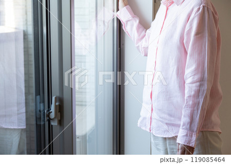 マンションの窓辺に立つミドル女性 119085464