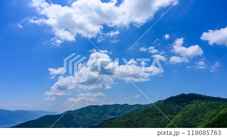 初夏の青空のもと、山頂に流れるたくさんの白い雲 初夏の青空のもと、山頂に流れるたくさんの白い雲 119085763