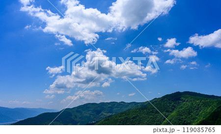 初夏の青空のもと、山頂に流れるたくさんの白い雲 初夏の青空のもと、山頂に流れるたくさんの白い雲 119085765