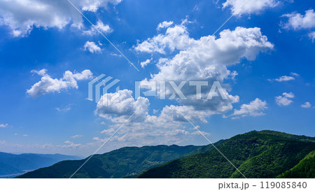 初夏の青空のもと、山頂に流れるたくさんの白い雲 初夏の青空のもと、山頂に流れるたくさんの白い雲 119085840