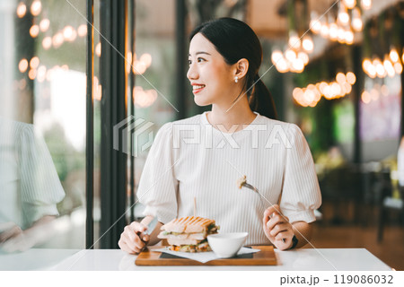 Asian woman healthy eating breakfast sandwich food diet meal at indoor cafe Asian woman healthy eating breakfast sandwich food diet meal at indoor cafe 119086032