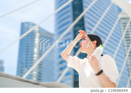 Business woman holding drinking water headache and thirsty heat stroke prevention from hot weather Business woman holding drinking water headache and thirsty heat stroke prevention from hot weather 119086049