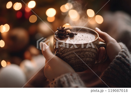 Warm embrace of hot chocolate held in hands surrounded by festive lights. Cozy atmosphere concept 119087018