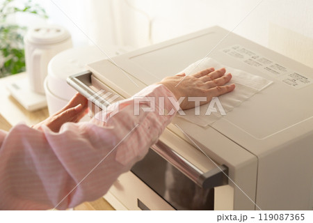 電子レンジの掃除をするミドル女性の手元 119087365