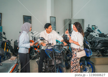 man trying out a new motorcycle and woman giving thumbs up 119088627
