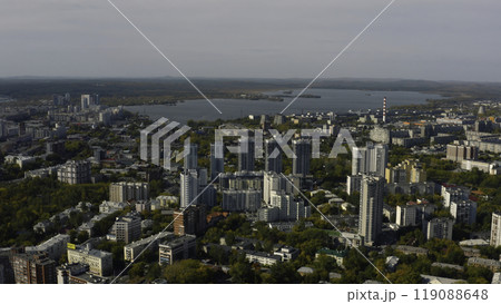 City with high-rise buildings on background of lake and green forest. Stock footage. Modern buildings in beautiful green city with lake and forest horizon. Top view of panorama of modern city in 119088648
