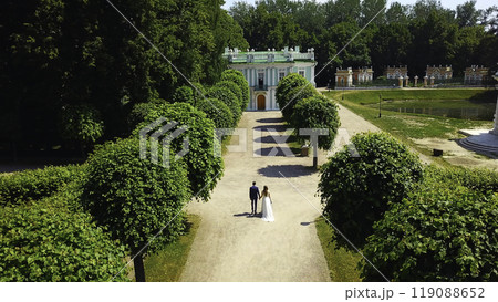 Top view of newlyweds in garden. Creative. Couple of newlyweds are walking in palace garden. Rich newlyweds on their wedding day in garden of ancient estate 119088652