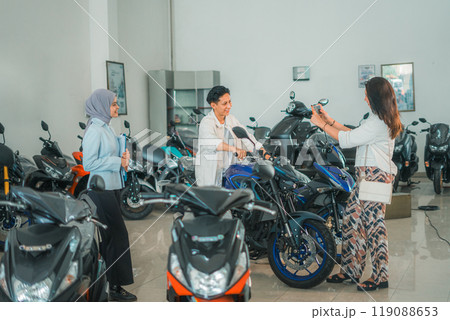 man on a new motorcycle taken by his girlfriend with a saleswoman 119088653