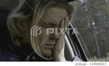 Young man with anxiety driving car. Stock. Close-up of man conveys emotions while driving car. Man with panic attack driving car on side of road 119088813