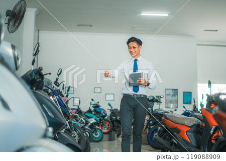 sales manager man carries a tablet while pointing at motorcycles 119088909