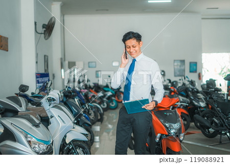 male sales manager calling and holding a motorcycle price list male sales manager calling and holding a motorcycle price list 119088921