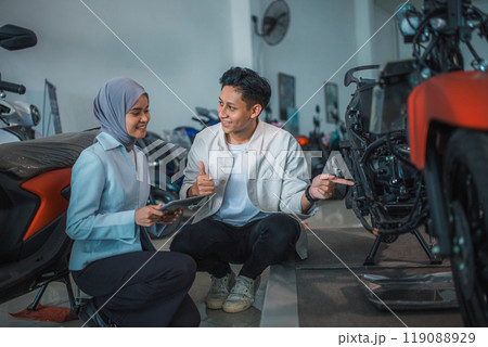 excited man and veiled saleswoman with a tablet checking the underframe excited man and veiled saleswoman with a tablet checking the underframe 119088929