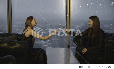 Attractive women clink glasses and drink champagne in restaurant. Media. Beautiful young women relax in champagne restaurant. Friends meet and celebrate with champagne in restaurant Attractive women clink glasses and drink champagne in restaurant. Media. Beautiful young women relax in champagne restaurant. Friends meet and celebrate with champagne in restaurant 119088950