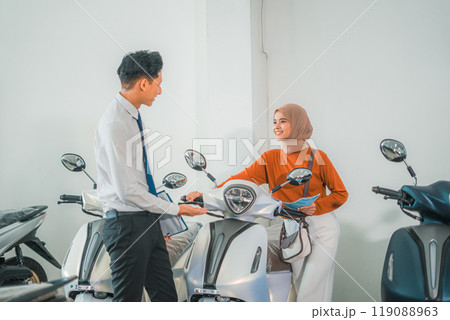 a female customer chooses a new motorcycle with a male salesperson 119088963
