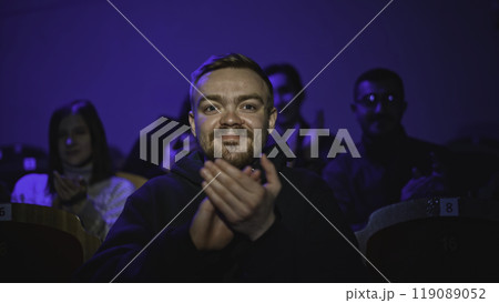 Young man is watching theatrical performance. Media. Man is watching theatrical performance in place. Spectator illuminated by spotlight at theatrical performance 119089052