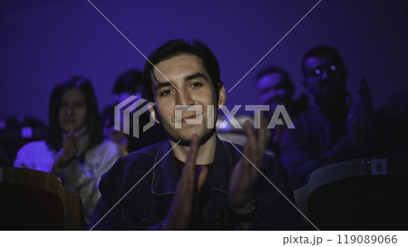 Young man is watching theatrical performance. Media. Man is watching theatrical performance in place. Spectator illuminated by spotlight at theatrical performance Young man is watching theatrical performance. Media. Man is watching theatrical performance in place. Spectator illuminated by spotlight at theatrical performance 119089066