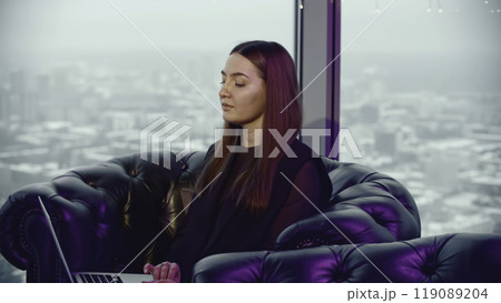 Young woman is working on laptop in restaurant. Media. Young woman is working on laptop in restaurant in background of city. Woman in lounge restaurant with laptop Young woman is working on laptop in restaurant. Media. Young woman is working on laptop in restaurant in background of city. Woman in lounge restaurant with laptop 119089204