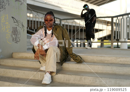 Sitting on City Steps Underneath Bridge, Wearing Sunglasses 119089525